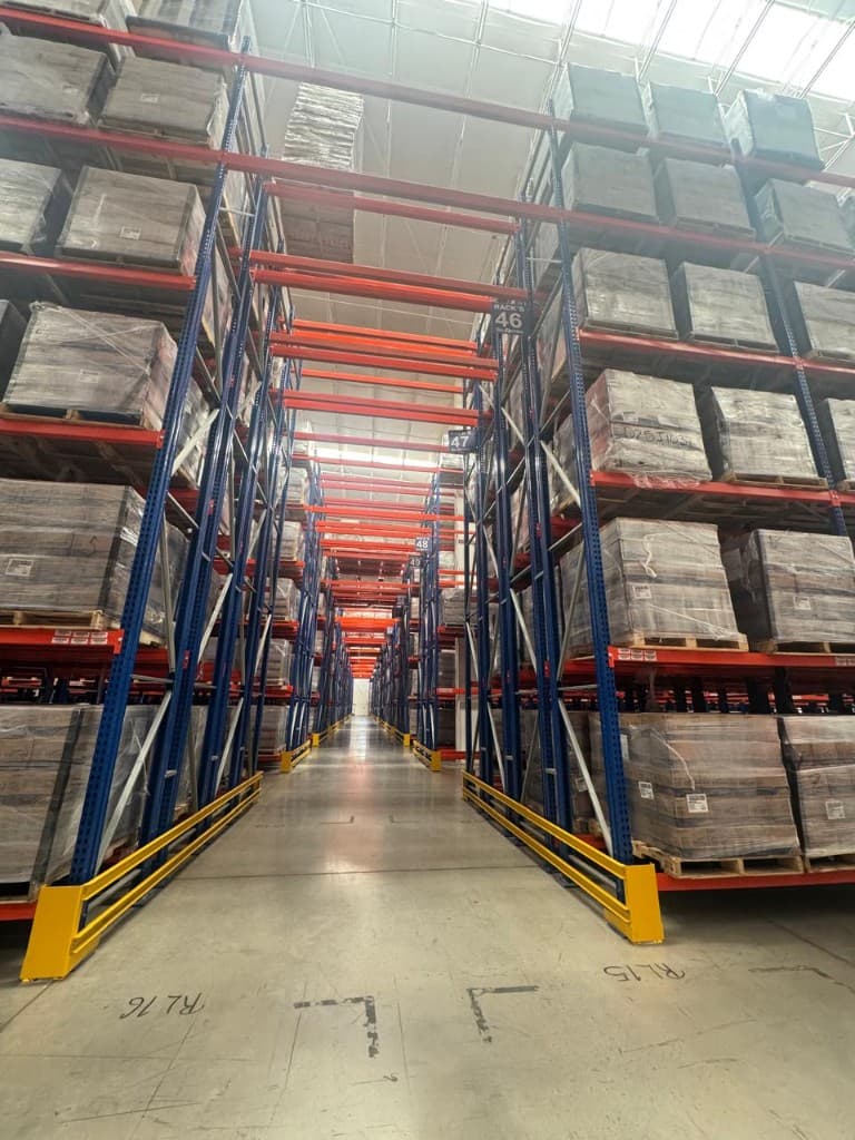Blue and orange rack aisle with location signage and shrink-wrapped stock in the Silodisa DC
