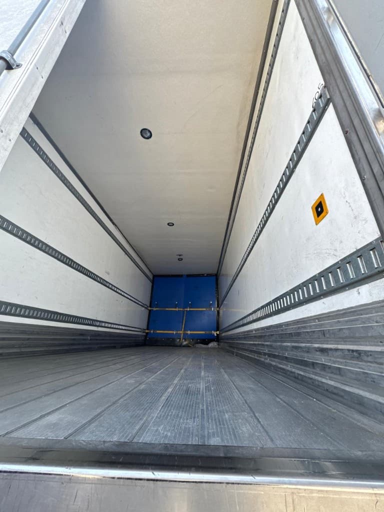 Reefer interior with blue thermal curtain and tie-down rails on the walls